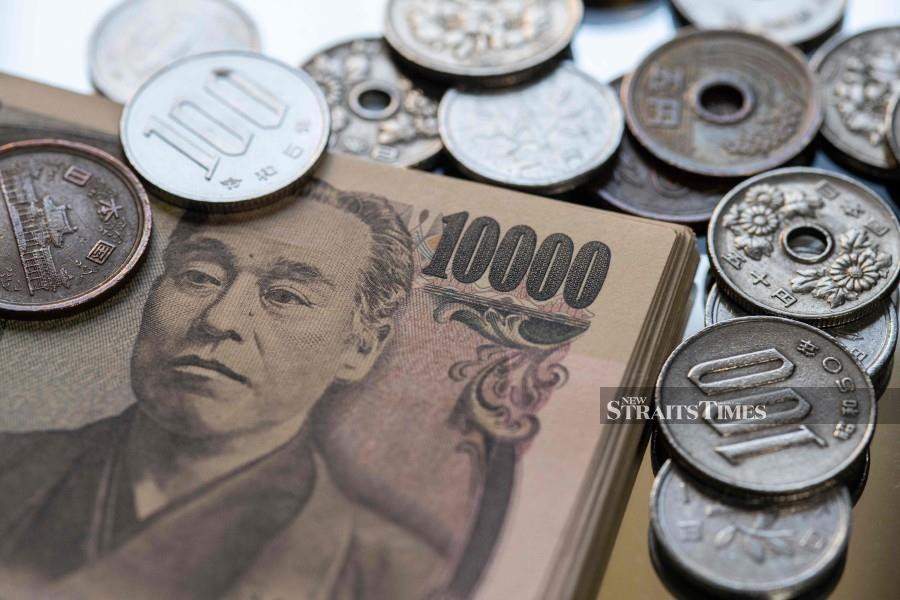 This photo illustration taken shows Japanese yen coins and 10,000 yen notes (65 USD) on display in Tokyo. (Photo by Richard A. Brooks / AFP)