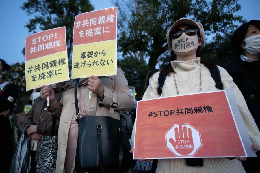 This picture taken on March 29, 2024 show people holding a banner saying "Protect children from joint custody after divorce" during a rally outside the National Diet Building in Tokyo against the Japanese government's plan to allow joint custody after divorce. AFP