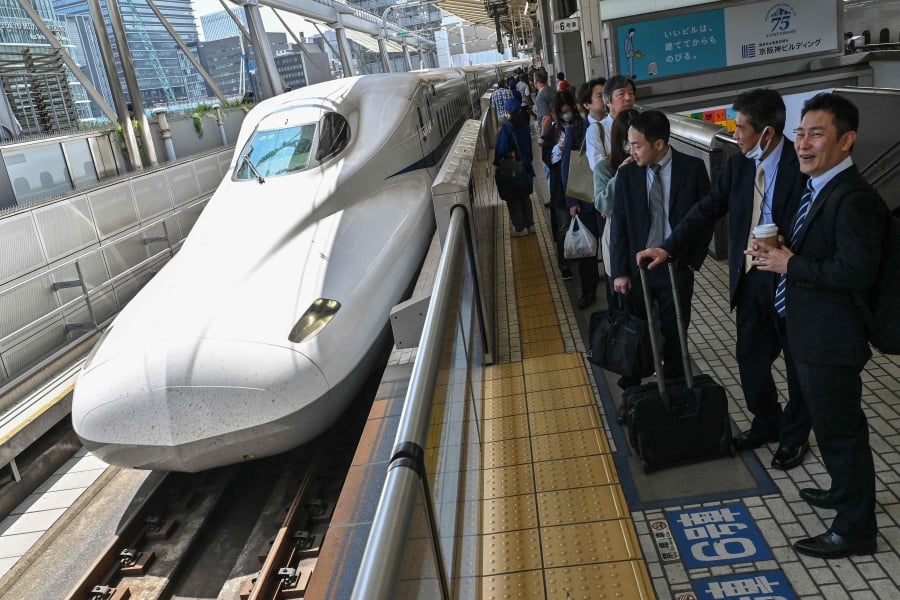 Passengers wait on the platform as a Kodama bullet train, or "shinkansen" service to the city of Nagoya arrives to pick up passengers at Tokyo station in central Tokyo. (Photo by Richard A. Brooks / AFP)