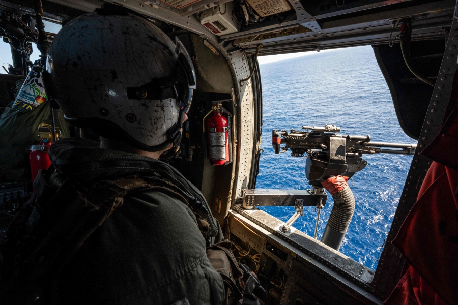 A flight crew member looks out from a helicopter launched from the USS Carl Vinson aircraft carrier on a flight to visit the Japan Maritime Self-Defense Force's Hyuga-class helicopter destroyer "JS Ise", during a three-day maritime exercise between the US and Japan in the Philippine Sea, between Okinawa and Taiwan. (Photo by Richard A. Brooks / AFP)