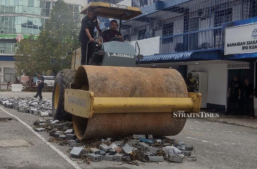 Kuantan police chief Assistant Commissioner Wan Mohd Zahari Wan Busu(left) looks on as the steamroller crushes the mining machines. - NSTP/ASROL AWANG