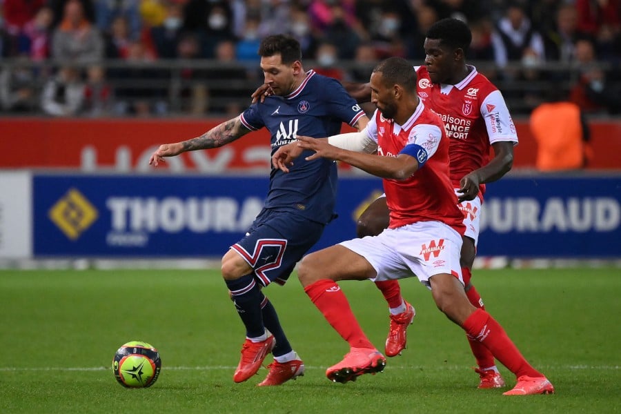 Reims' Zimbabwean midfielder Marshall Munetsi (R) and Reims' Moroccan Yunis Abdelhamid fight for the ball with Paris Saint-Germain's Argentinian forward Lionel Messi during the French L1 football match between Stade de Reims and Paris Saint-Germain at Auguste Delaune Stadium in Reims on August 29, 2021. (Photo by FRANCK FIFE / AFP)