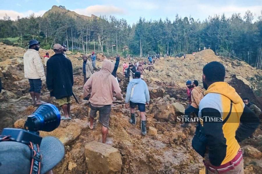 People gather at the site of a landslide in Maip Mulitaka in Papua New Guinea's Enga Province on May 24, 2024. Local officials and aid groups said a massive landslide struck a village in Papua New Guinea's highlands on May 24, with many feared dead. - AFP pic