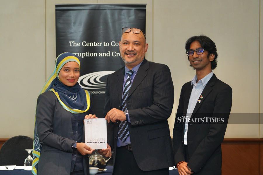 KUALA LUMPUR : Nurbani Shuhada (left) receiving a "Structuring the Malaysian Ombudsman Office" research report from Chief Executive Officer of The Centre to Combat Corruption and Cronyism (C4 Centre), Pushpan Murugiah (middle) during the Report Launch by The Center to Combat Corruption and Cronyism here in Kuala Lumpur. — STU/AIMAN FARHAN