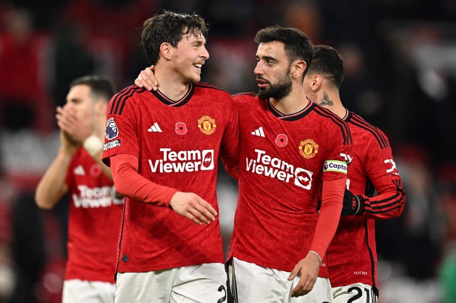 Manchester United's Swedish defender Victor Lindelof (left) is congratulated by Manchester United's Portuguese midfielder #08 Bruno Fernandes at the end of the English Premier League football match between Manchester United and Luton Town at Old Trafford in Manchester, north west England. Manchester United wins 1 - 0 against Luton Town. — AFP pic