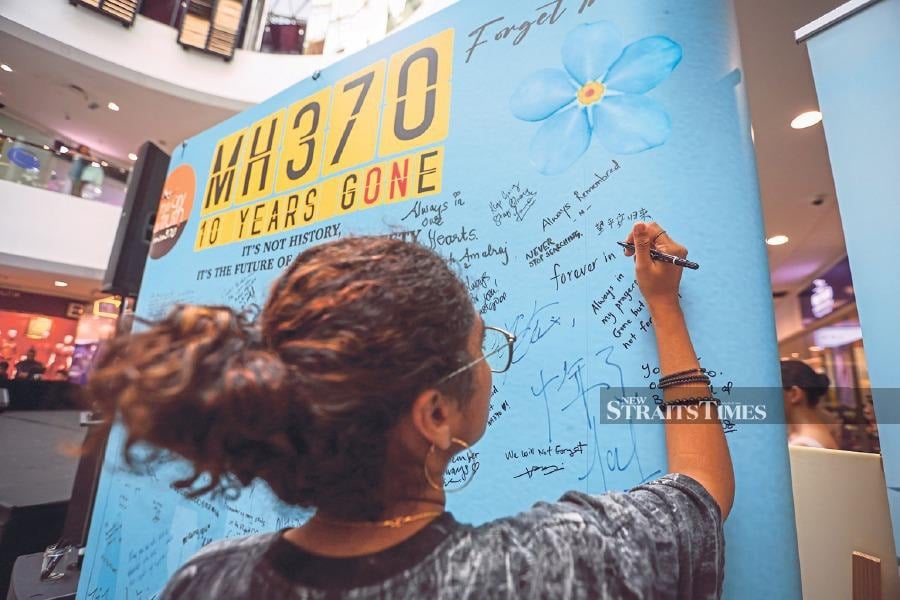 A shopper writing a message on a whiteboard to commemorate the 10th anniversary of MH370 at Empire Subang mall. - NSTP/ ASWADI ALIAS