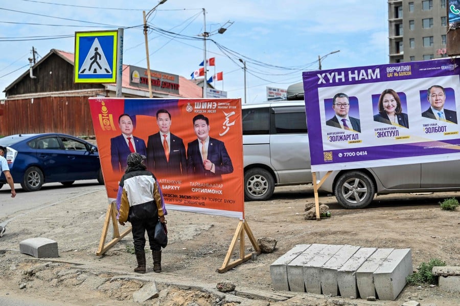 A woman looks at posters of candidates for the parliamentary elections on a street in Ulaanbaatar on June 25, 2024. AFP