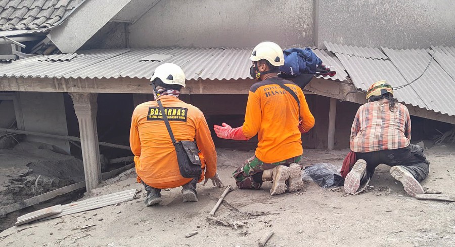 A handout photo made available by the Indonesian national search and rescue agency (BASARNAS) shows rescuers inspecting a house covered by volcanic ash from the Mount Semeru eruption at a village in Lumajang, East Java, Indonesia, 05 December 2021. The volcano erupted on 04 December 2021 leaving a number of people killed and missing. - EPA pic