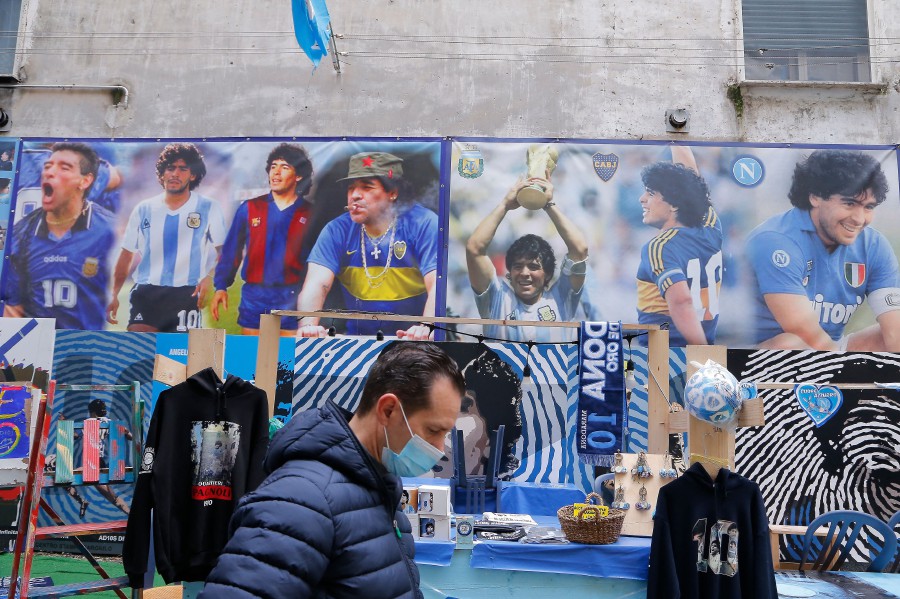 A stands by posters in homage to late Argentinian football legend Diego Maradona is pictured at the so-called "Maradona square" in the Quartieri Spagnoli district of Naples. - AFP PIC
