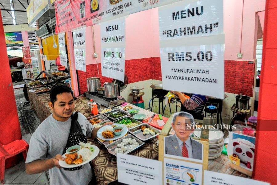 A customer carrying two plates of food away from a stall offering the Rahmah Menu at a food court in Cyberjaya, on Monday. -NSTP/ AIZUDDIN SAAD