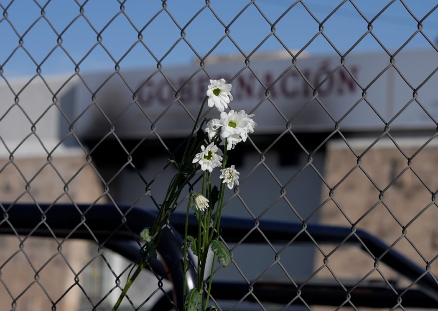 Wilted flowers hang from the fence outside an immigration detention center where a fire killed at least 40 people, in Ciudad Juarez, Mexico. (AP Photo/Fernando Llano)