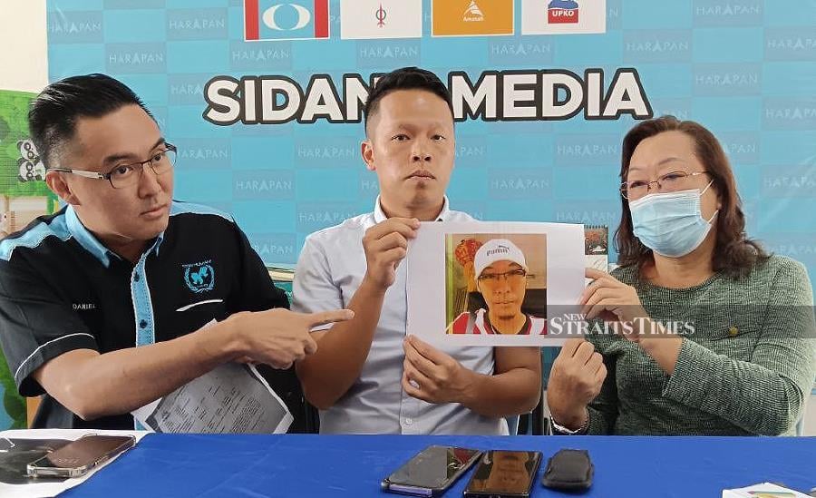 Housewife Chang Moi Lin with a picture of her missing son with Semambu assemblyman Chan Chun Kuang (middle) and Malaysia International Humanitarian Organisation public relations officer Daniel Khoo (left) at Chan’s service centre. - NSTP/ ASROL AWANG