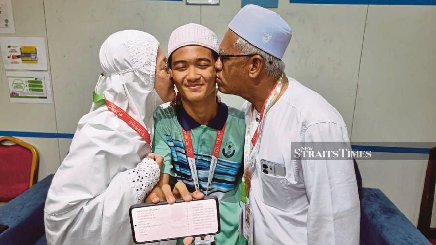 Muhammad Ameer Che Noor Azam (centre) is congratulated by his parents after sharing his SPM 2023 results. - Husain Jahit.