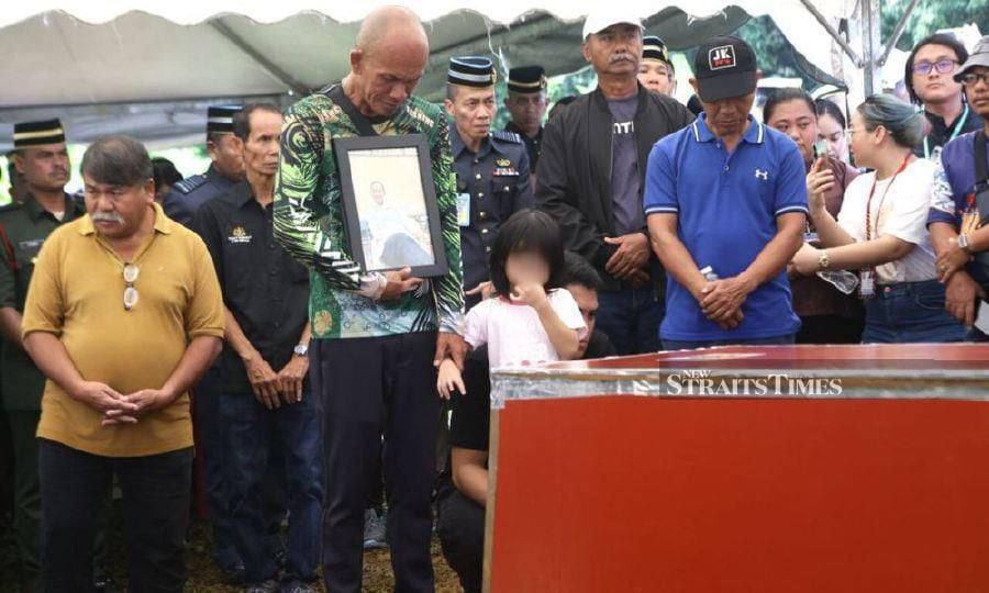 SERIAN: Allesia Felice Haslie, 4, looks on at the casket of her mother, Joanna Felicia Rohna, during the burial at the Kampung Engkaroh Christian Cemetery in Serian today (April 25). — STR / NADIM BOKHARI