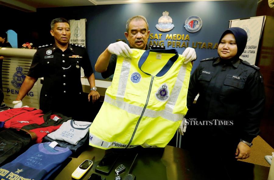 North Seberang Prai police chief Assistant Commissioner Noorzainy Mohd Noor (center) shows police vest that has been seized from four individuals disguise as policemen and blackmail foreigners during a press conference at the North Seberang Perai District Police Headquarters in Penang. -NSTP/RAMDZAN MASIAM