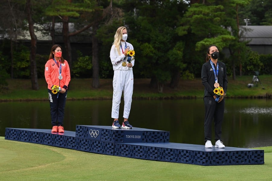 (From L to R): Silver medallist Japan's Mone Inami, gold medallist USA's Nelly Korda and bronze medallist New Zealand's Lydia Ko stand on the podium during the victory ceremony of the women�s golf individual stroke play during the Tokyo 2020 Olympic Games at the Kasumigaseki Country Club in Kawagoe on August 7, 2021. (Photo by Kazuhiro NOGI / AFP)