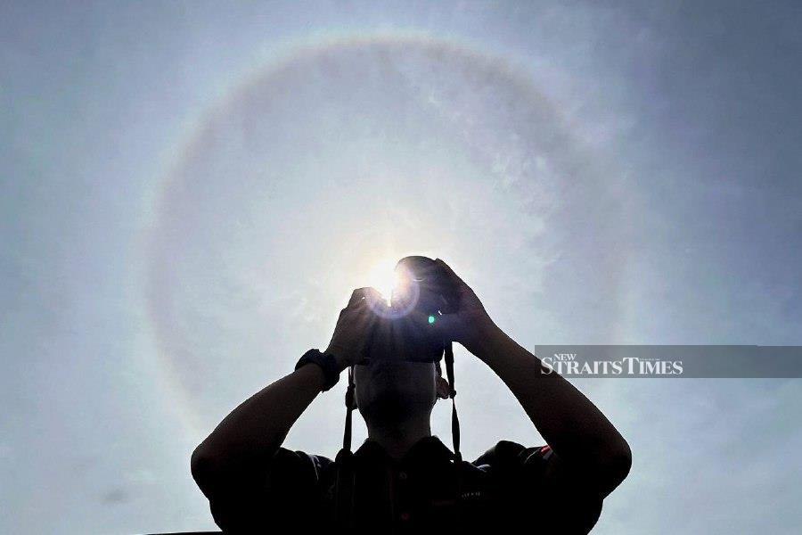LABUAN: A photographer captures the background of the sun’s halo phenomenon during the Annual Malaysian Fire and Rescue Department (JBPM) parade in Labuan. – BERNAMA PIC