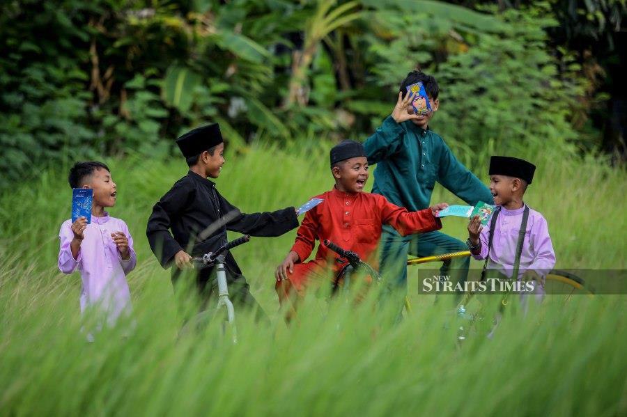 KUALA TERENGGANU: Zaquan Asraf Zakaria, 10 (middle), with friends after receiving 'duit raya' in Kampung Gelong Gajah. - NSTP/GHAZALI KORI