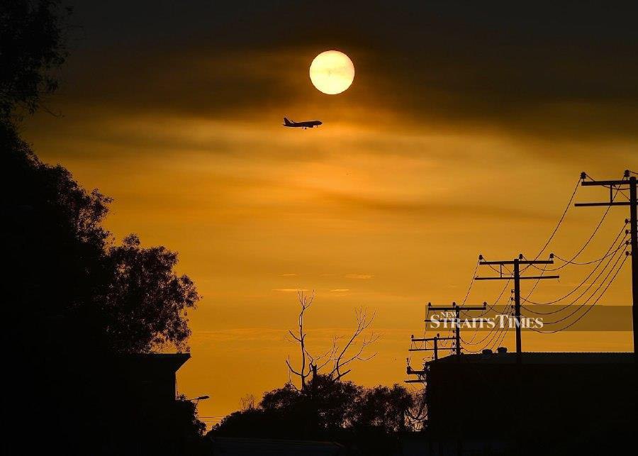 PUTATAN: An airplane silhouette captured against the fiery backdrop of the sun. -- NSTP/ADAM ARININ