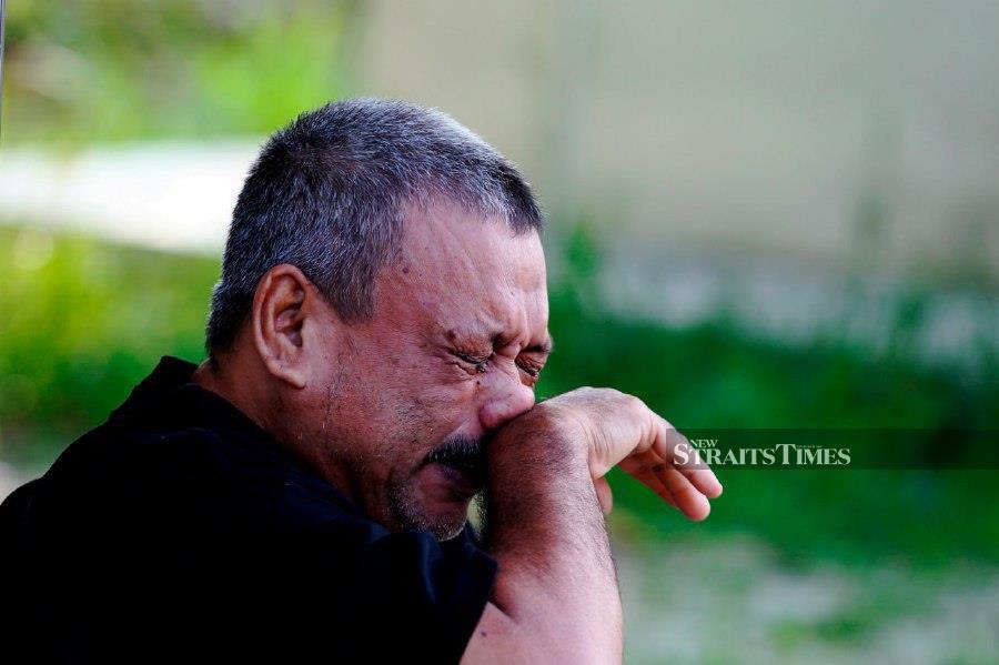 IPOH: Muhd Zamrie Zainal Abidin couldn't hold back his tears while visiting the grave of his youngest child, Mohammad Zaharif Affendi at a cemetery near here. -- BERNAMA PIC