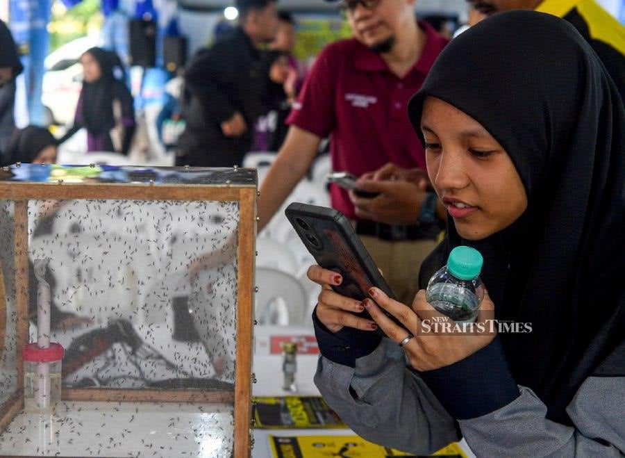 NILAI: Universiti Sains Islam Malaysia (USIM) student Nurhusna Sukri capturing images of Wolbachia mosquitoes while visiting the booth during the launch event of the Aedes Mosquito Release Programme with Wolbachia in Zone A, Desa Anggerik. -- BERNAMA PIC