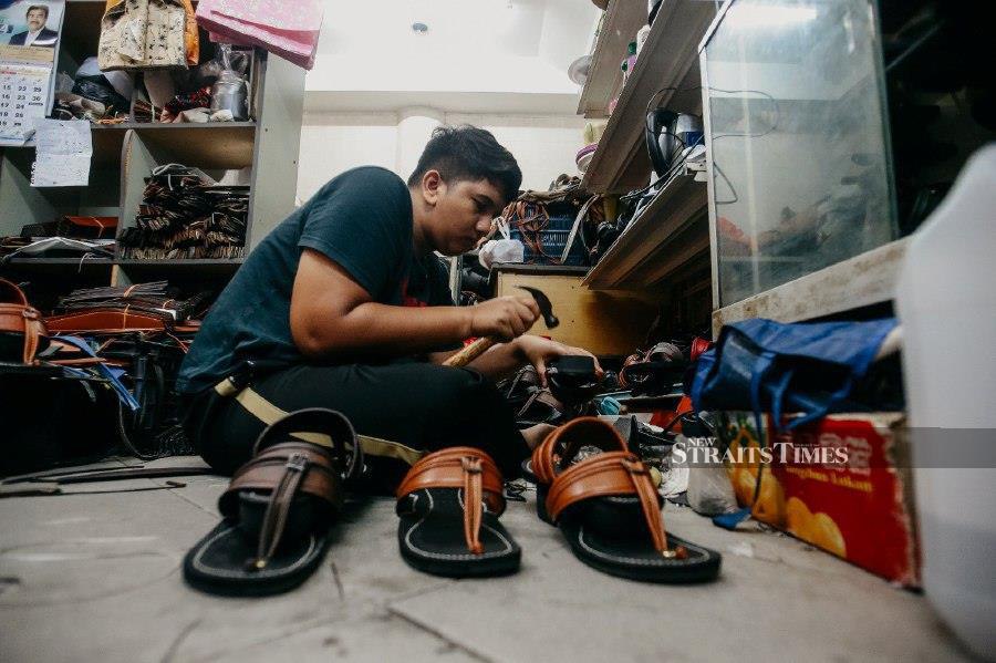 KUALA LUMPUR: Aiman Hakim, son of the owner of Tapak Capal Cap Kancil Emas, prepares the traditional footwear for the Malays at Keramat Mall. - NSTP/GENES GULITAH