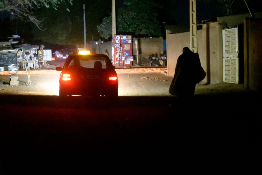 A woman walks past taxi during a black out affecting some districts of the Niger capital Niamey. -  AFP pic