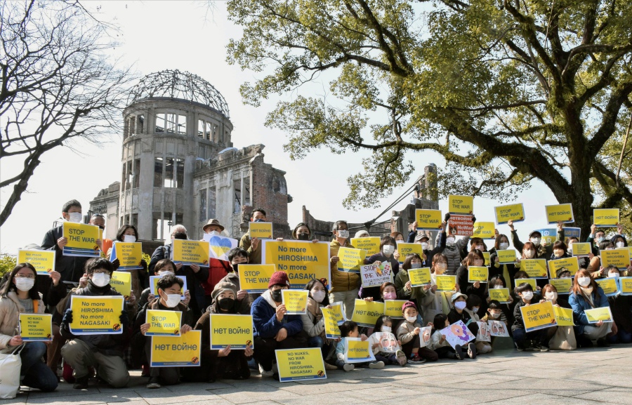 FILE - People show posters that read, "Stop the war, No more Hiroshima, No more Nagasaki, No nukes, No war," during a protest against Russia's invasion of Ukraine, as they gather at Hiroshima Peace Memorial Park in Hiroshima, western Japan, on Feb. 26, 2022. By ending 77 years of almost uninterrupted peace in Europe, war in Ukraine war has joined the dawn of the nuclear age and the birth of manned spaceflight as a watershed in history. After nearly a half-year of fighting, tens of thousands of dead and wounded on both sides, massive disruptions to supplies of energy, food and financial stability, the world is no longer as it was. - (Eriko Noguchi/Kyodo News via AP)