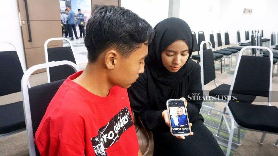  Nurul Fatin Hanani Azmi, 23 and her younger brother Adam Irfan, 15, look at a picture of their late parents who were killed in a road accident on Jan 11 last year. — NSTP / NOORAZURA ABDUL RAHMAN
