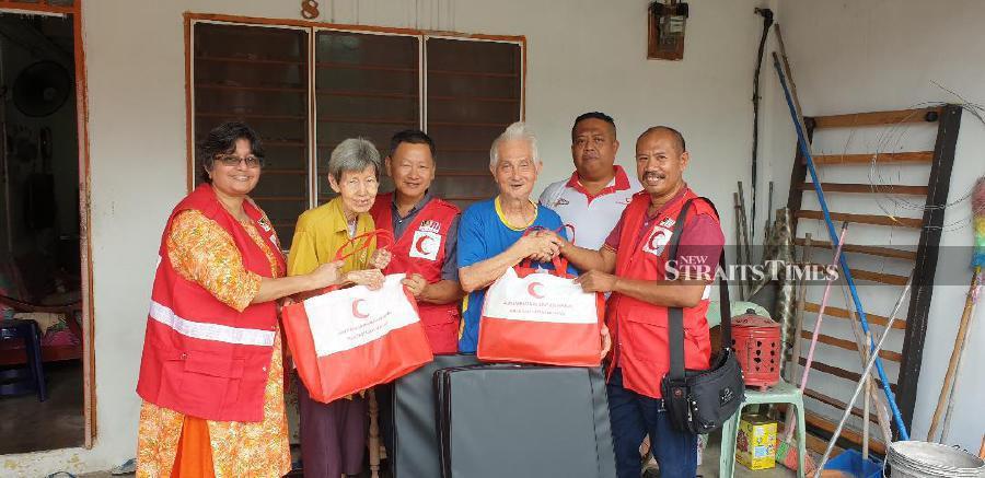 Lekha Nandey (far left) and members of the MRC (in red jackets) presenting the items they brought to Yong Quat Thai (third from right) and Chua Ah Luang (second from left). - NSTP/VINCENT D’SILVA