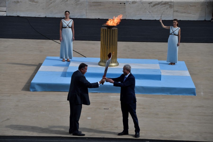 IOC vice-president Yu Zaiqing (R) receives the torch with the Olympic Flame, from the hands of President of the Hellenic Olympic Committee and IOC member Spyros Capralos (L), during the handover ceremony of the Olympic Flame for the Beijing 2022 Winter Olympics at Panathinean stadium in Athens, on October 19, 2021. - The Olympic flame has been lit once again in an empty stadium on October 18, 2021, as it starts its truncated journey to Beijing for the Winter Games in February. Like the ceremony in March 2020 to light the flame for Tokyo, and like those Games, which were put back a year, Monday's ceremony is a victim of coronavirus restrictions. - AFP pic