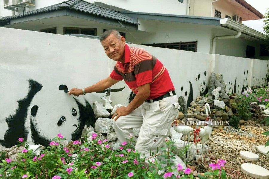 A hobby – retired JPJ officer Patrick Wee, 68, and his panda painting outside his home in Kuching. Photo by Goh Pei Pei.