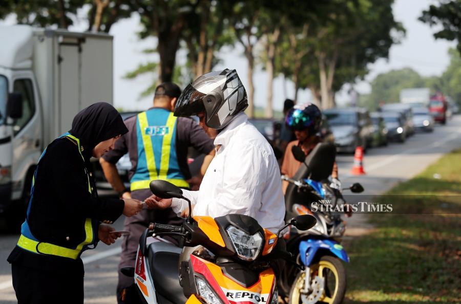 (File pix) An RTD officer checking a motorcyclist’s documents at a roadblock. Pix by NSTP/Rasul Azli Samad 