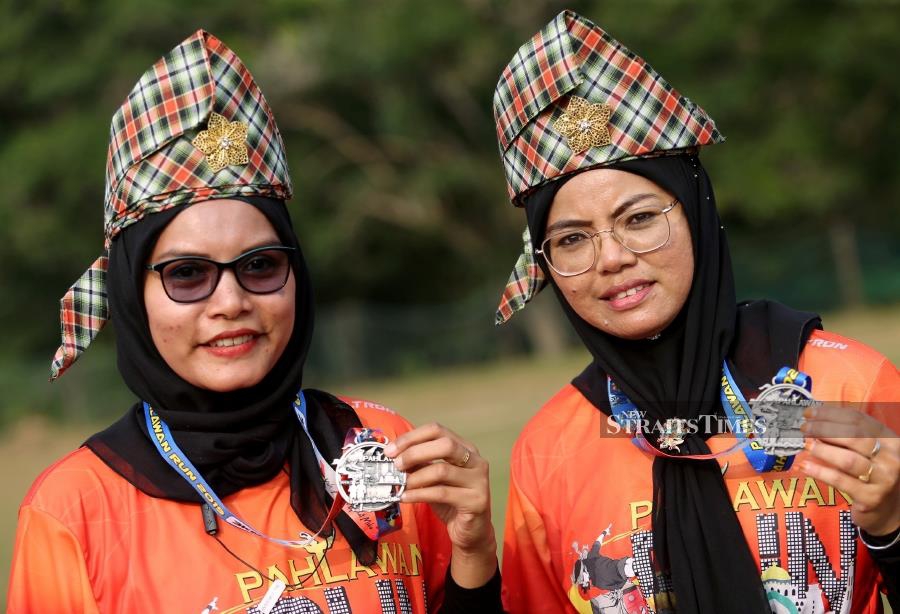 Another participant, Asbiah Sabtu (left), 41, said she spent more than two hours yesterday to prepare five tanjaks made from kain pelikat to be worn by her sisters and friends in the race. NSTP/RASUL AZLI SAMAD