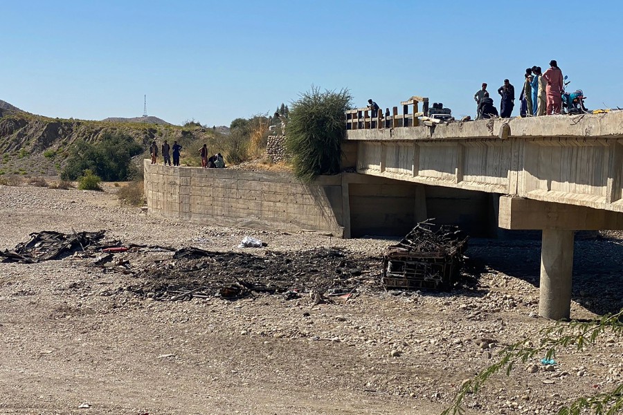 Residents gather over a bridge to watch the wreckage of a burnt passenger bus in Lasbela district of Pakistan's Balochistan province on January 29, 2023. - At least 40 people died when a bus plunged off a bridge in southwestern Pakistan and burst into flames, a government official said on January 29. -AFP PIC