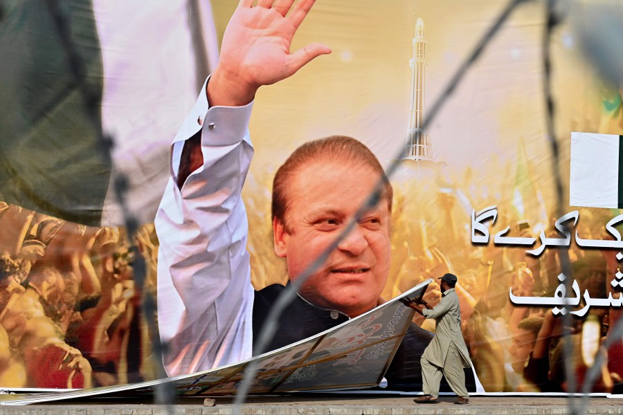 A labourer works near a large banner of Pakistan's former Prime Minister Nawaz Sharif at a park ahead of his arrival in Lahore on Oct 19, 2023. -- AFP