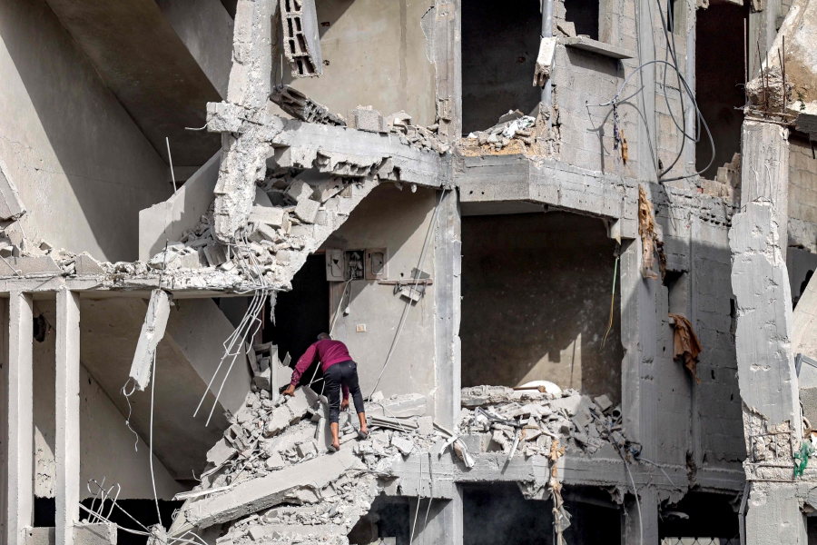 A man inspects the wreckage of a partially-collapsed building due to Israeli bombardment in Gaza City. (Photo by AFP)
