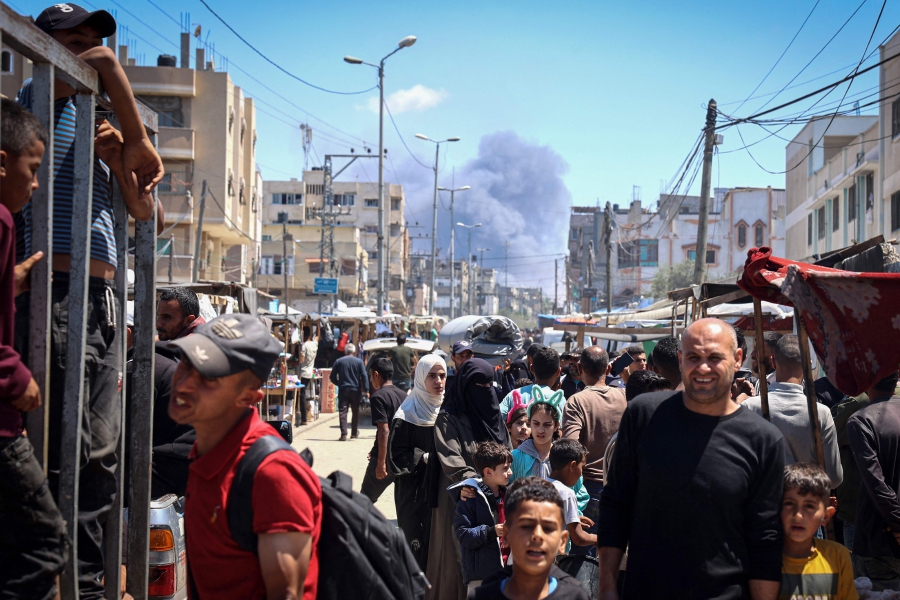 Palestinians crowd a street as smoke billows nearby from Israeli strikes in Rafah in the southern Gaza Strip, amid the ongoing conflict between Israel and Hamas. (Photo by AFP)