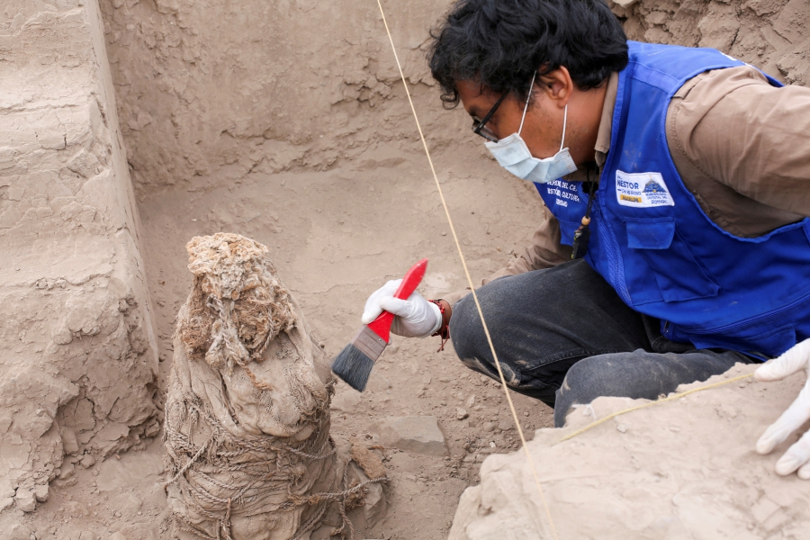 An archaeologist works on one of five mummies, that according to archaeologists belong to the pre-Inca Ychsma culture that inhabited the central coast of Peru from approximately 900 to 1450 AD., at the Huaca La Florida archaeological site, in Lima, Peru. (REUTERS/Anthony Marina)