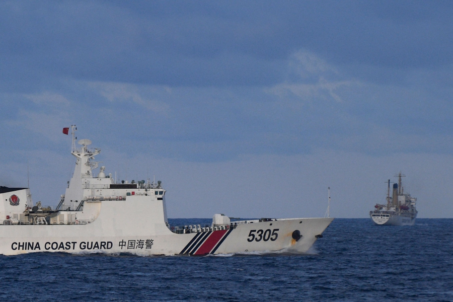 A Chinese Coast Guard ship sails near a Philippine vessel (right) that was part of a convoy of civilian boats in the disputed South China Sea. (Photo by TED ALJIBE / AFP)