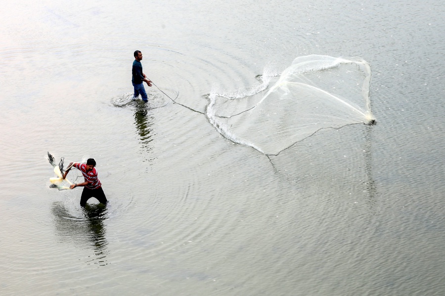 KUALA TERENGGANU: Residents cast nets as they try and attempt to catch fish at the Kuala Ibai river estuary, where the water level has receded due to current hot weather. — NSTP/GHAZALI KORI