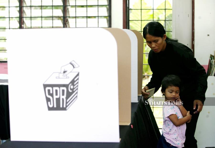 Seen here is an Orang Asli woman casting her ballot at the Peretak Education Development Centre in Kampung Orang Asli, Peretak.- PIC NSTP/EIZAIRI SHAMSUDIN