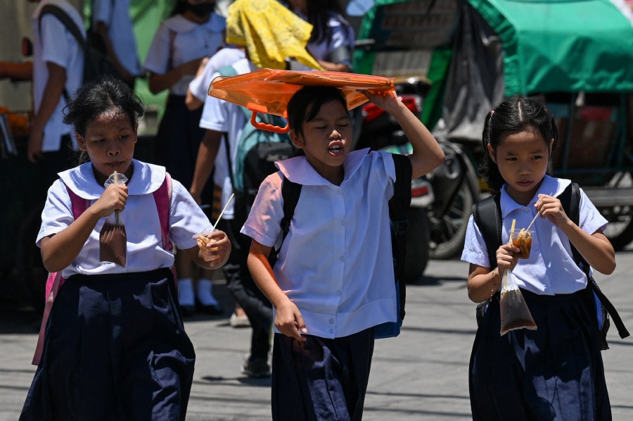 A student uses an envelop to protect herself from the sun during a hot day in Manila. More than a hundred schools in the Philippine capital shut their classrooms on April 2, as the tropical heat hit "danger" levels, education officials said. - AFP pic