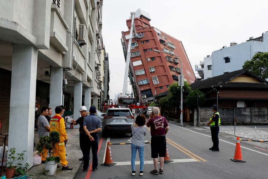 People look on as workers carry out operations while on an elevated platform of a firefighting truck at the site where a building collapsed, following the earthquake, in Hualien, Taiwan April 4, 2024. REUTERS PIC
