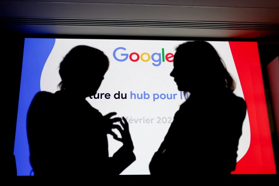 People are silhouetted in front of a Google logo during the inauguration of a new hub in France dedicated to the artificial intelligence (AI) sector, at the Google France headquarters in Paris, France, February 15, 2024. - REUTERS pic