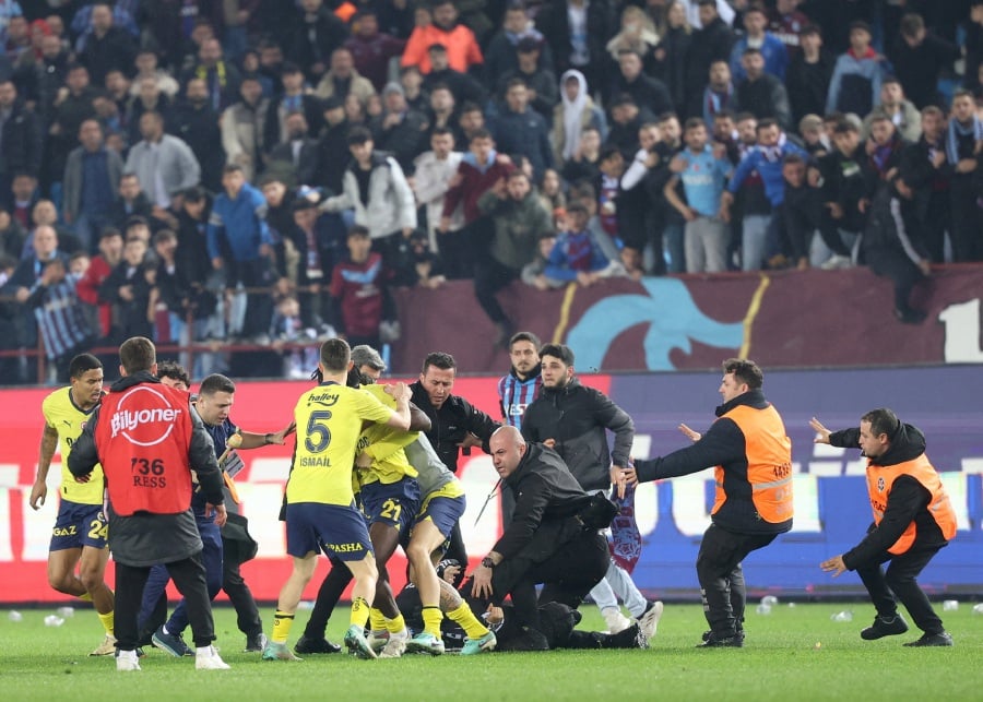 Trabzonspor fans invade the pitch and clash with Fenerbahce players and security staff after the match. - REUTERS/Depo Photos