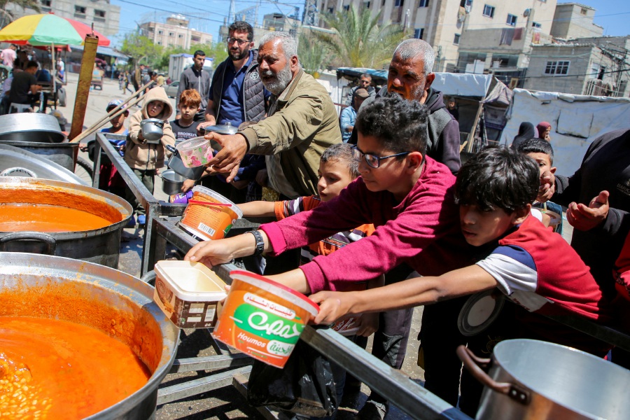 Palestinians gather to receive food cooked by a charity kitchen, amid shortages of aid supplies, after Israeli forces launched a ground and air operation in the eastern part of Rafah, as the ongoing conflict between Israel and Hamas continues, in Rafah, in the southern Gaza Strip May 8, 2024. - REUTERS