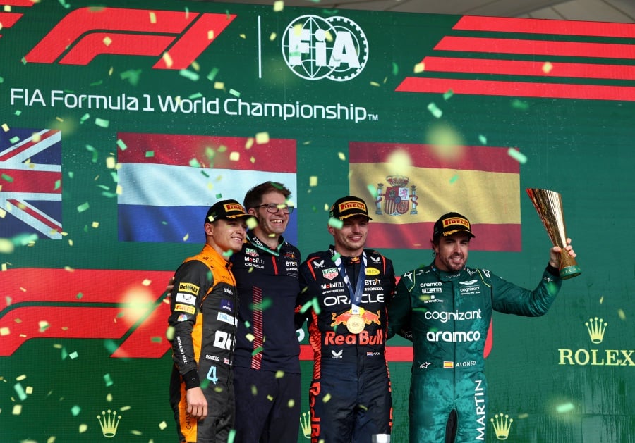 Second placed Lando Norris of McLaren, a Red Bull team member, first placed Max Verstappen of Red Bull and third placed Fernando Alonso of Aston Martin celebrate on the podium during the trophy presentation for the Brazilian Grand Prix.- REUTERS