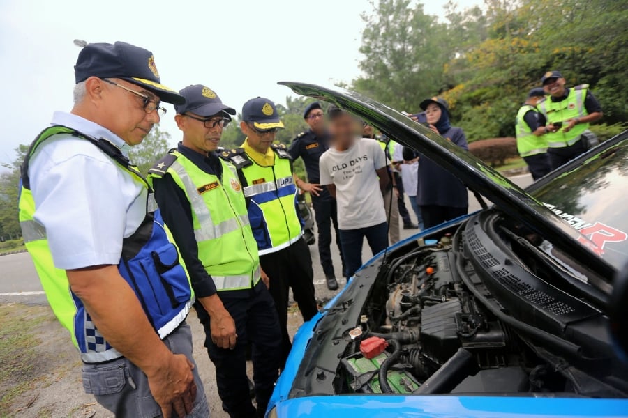 RTD senior enforcement director Datuk Lokman Jamaan (left) with his officers inspecting an engine of a vehicle stopped during its Integrated Motorcycle Operations in conjunction with the festive season in Meru Raya. - BERNAMA PIC