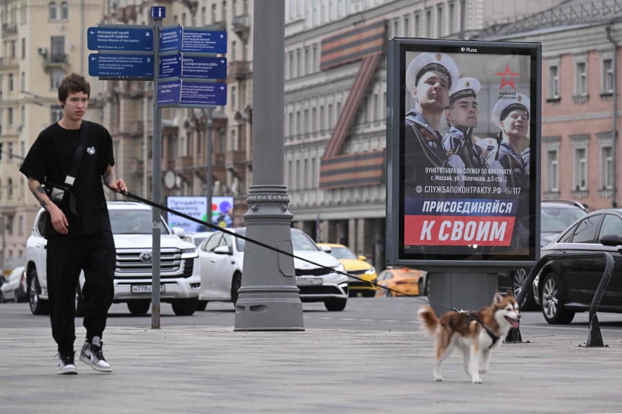 A poster promoting contract army service and reading "Join your people" sits on the side of the Garden Ring road, with a theatre building adorned with the letter Z formed by a huge Russia's patriotic black and orange Saint George's ribbon - which has become a symbol of support for Russian military action in Ukraine - seen in the background, in central Moscow on July 7, 2023. -AFP PIC